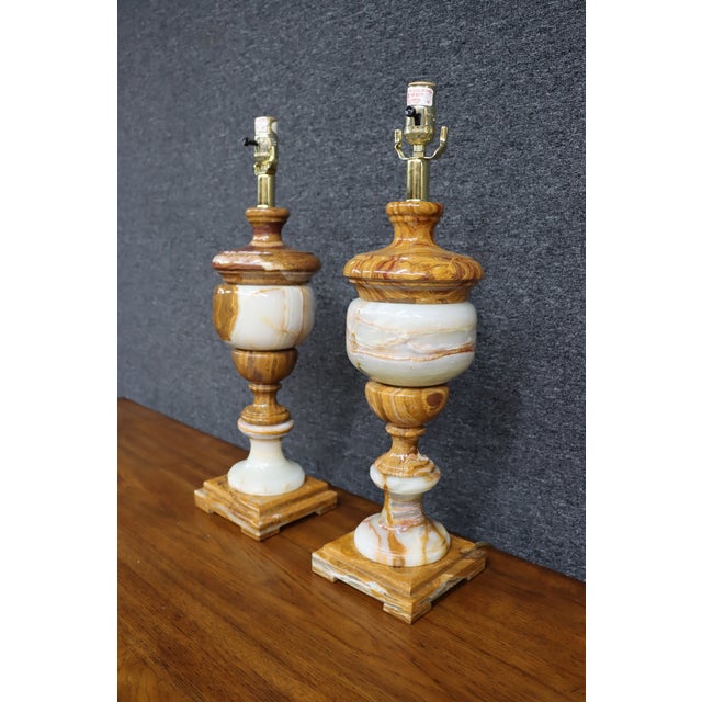 Pair of Italian Neoclassical table lamps featuring richly veined honey-toned and white alabaster in a classic urn form....