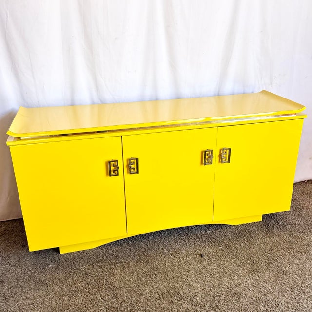A bold and refined postmodern credenza finished in a high-gloss yellow laminate, blending sculptural form with...