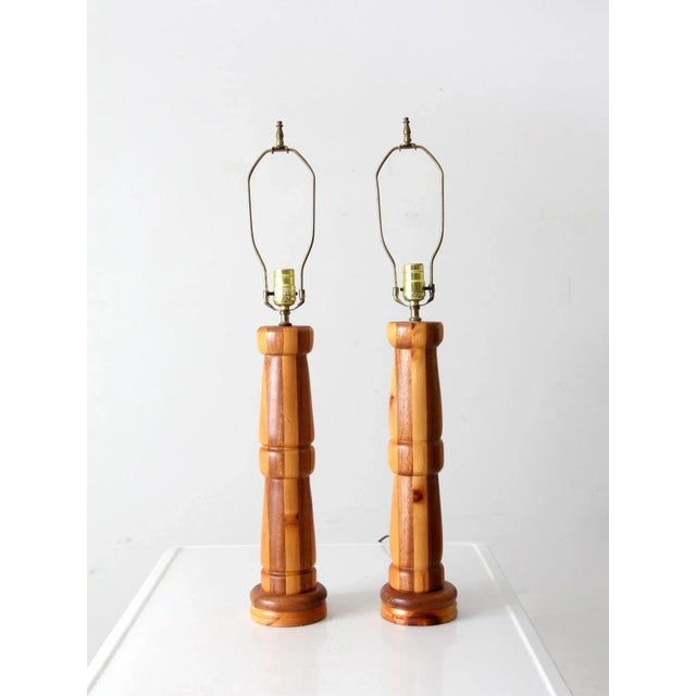 his is a pair of vintage wooden table lamps. The hand turned wooden lamps feature a two-tone striped design. They have...