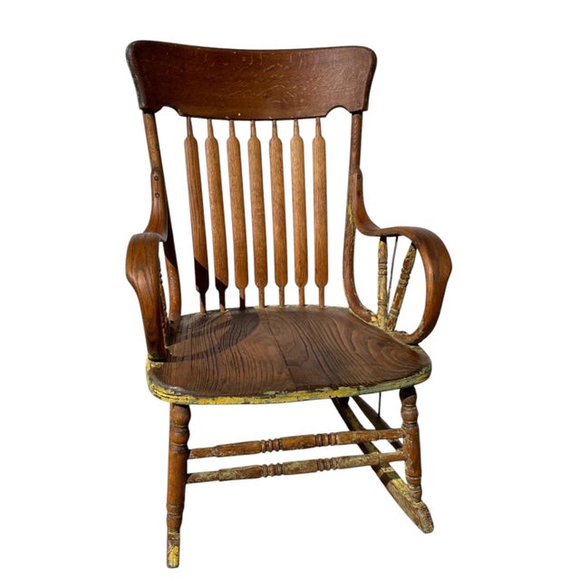 A charming Antique Windsor-style rocking chair featuring a classic comb back design with turned spindle supports and...