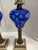 The product is a pair of antique Victorian-style oil lamps made of cut-to-clear cobalt blue glass, brass, and marble....