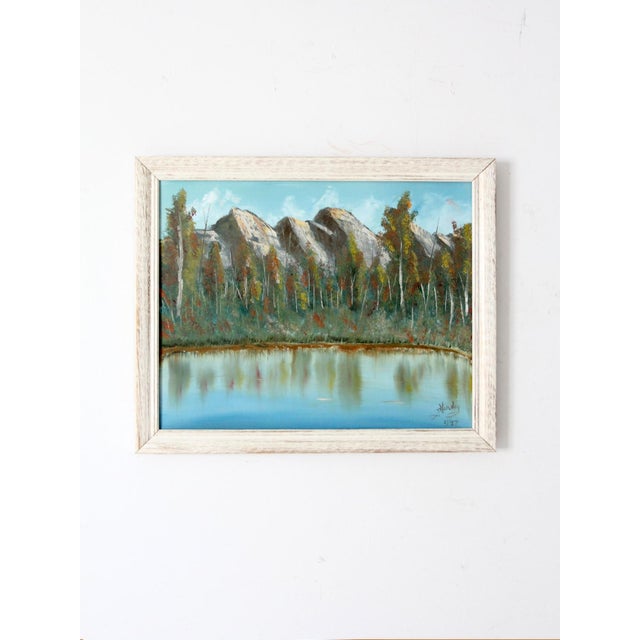 This vintage canvas painting features a serene lake bordered by aspen trees, with softly rendered mountains fading into...