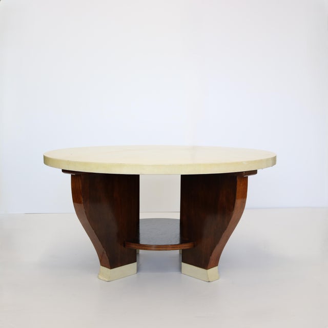Modernist beautiful hardwood two-tier circular cocktail table with a parchment covered top. The base consists of four...