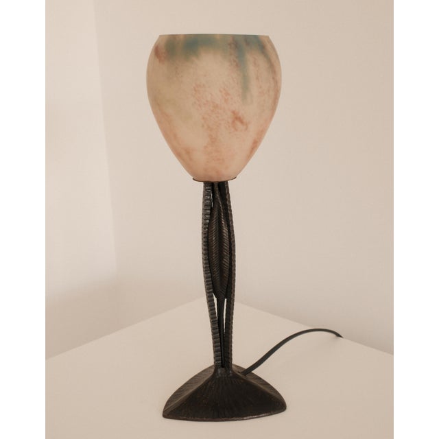 An elegant and sculptural Art Deco table lamp is distinguished by its finely worked patinated metal base, composed of...