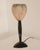 Art Deco table lamp, France, circa 1925. A finely worked metal stem gives the lamp its vertical poise, contrasted by the...