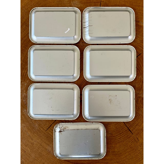 This antique white plate, part of a vintage set of seven tin snack plates, snack trays, tip trays, or catchall for...