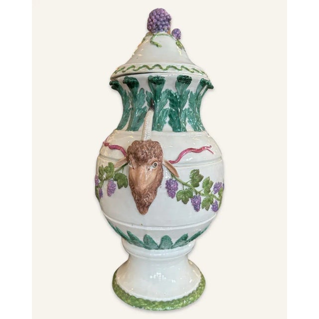 This Ginori covered urn is decorated in leaves, vines and grapes in low relief and ram’s heads as handles in high relief....