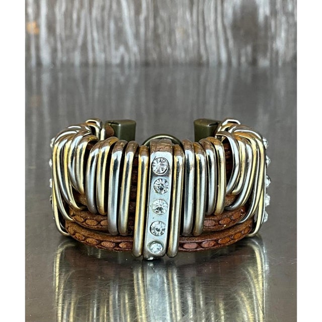 This vintage cuff bracelet is built from a dense arrangement of curved, ribbed metal bands in mixed silver and gold tones,...
