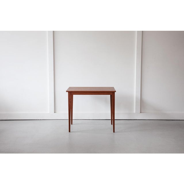 A lovely teak side table or coffee table, featuring lovely grain patterning on its top and long, elegant legs. An...