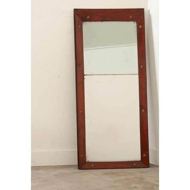 A slender, 19th century French Empire mirror with its original glass plates. The frame is made of beveled mahogany...