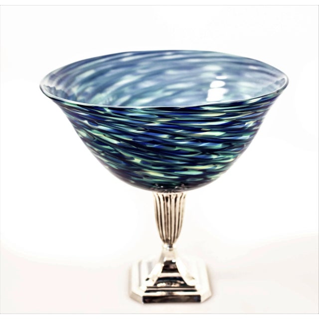 Different shades of blue, from light to dark with touches of pale yellow blend together in the glass like waves in an...