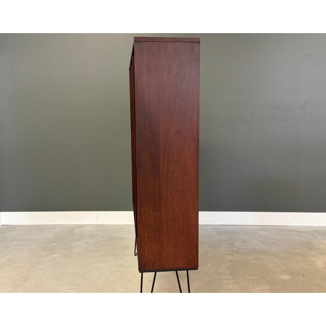 A mid century modern walnut bookcase with lots of shelves sitting on hairpin legs. 54” wide. 12.25” deep. 61.5” tall.