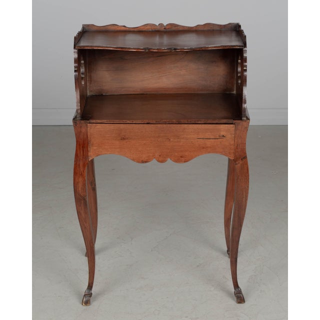 An early 19th century Louis XV country French side table or nightstand made of solid walnut, with pierced quatrefoil...