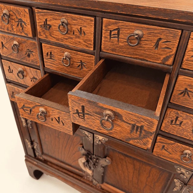 A Korean apothecary chest with sixteen small drawers above a two-door cupboard. Chests like this were made for village...
