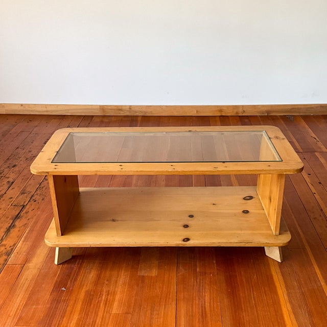 Handmade folk art style coffee table. Rounded rectangular shape with angled feet and a glass top.