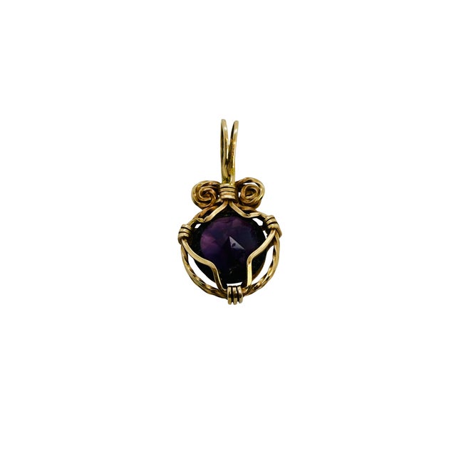 A rich purple amethyst is the centerpiece of this pendant, set in 14 karat yellow gold with scrolled accents and twisted...