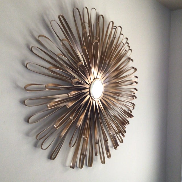 Striking Metal flower design with a small mirror center. Lots of looped metal surround a small mirror to create a floral...