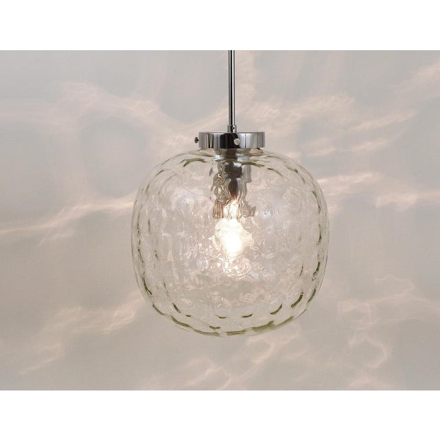A beautiful Space Age pendant light with a large clear glass globe and chrome-plated hardware. The globe is hand blown and...