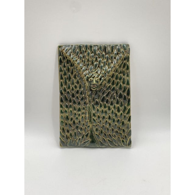 A wall object / art object * Wall panel made of ceramic * A face in the center of an organic-looking structure, an entire...