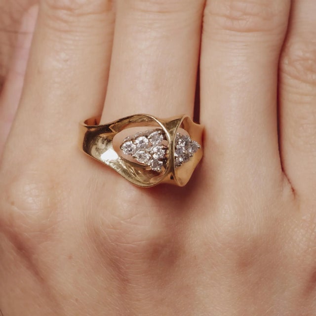 This vintage 1970’s 14k yellow gold ring showcases twelve radiant round brilliant diamonds, offering a bold yet refined...