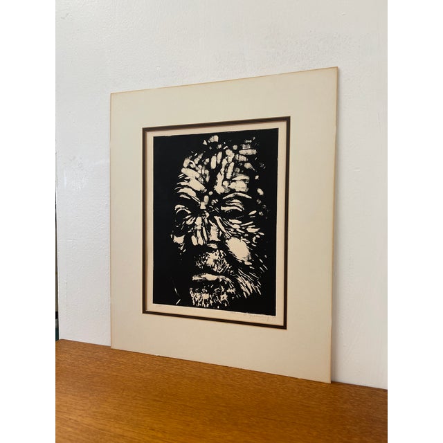 Vintage black and white portrait print depicting a highly expressive human face rendered in strong contrast. The...