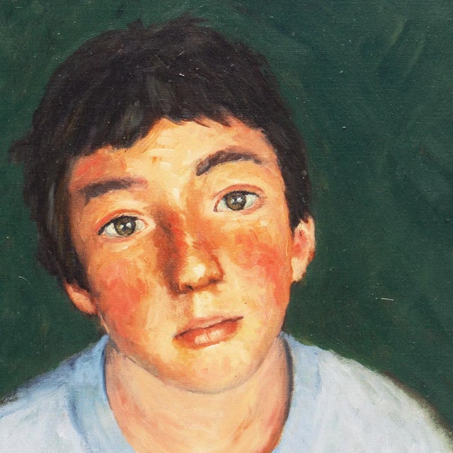 American School portrait of a boy in a soft blue shirt contrasted against a dark green background gazing candidly at the...