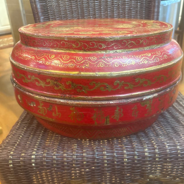 This round, red-and-gold hand-decorated Chinese lacquered wedding or stacking box features intricate gilt floral and...