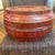 This round, red-and-gold hand-decorated Chinese lacquered wedding or stacking box features intricate gilt floral and...