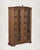 A carved finial at the crown. An arched pediment. Ten individual glass panes per door. This antique Indian armoire is...