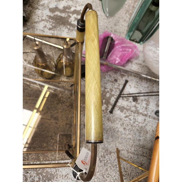 This vintage French bar cart features a golden brass frame paired with smoked glass shelves, resting on petite caster...