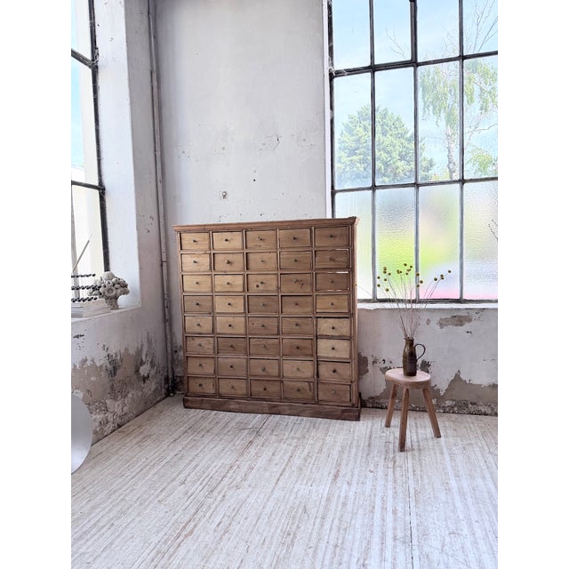 A vintage pine workshop cabinet with numerous drawers, dating from the 1950s. We love its tall, shallow profile. Its many...