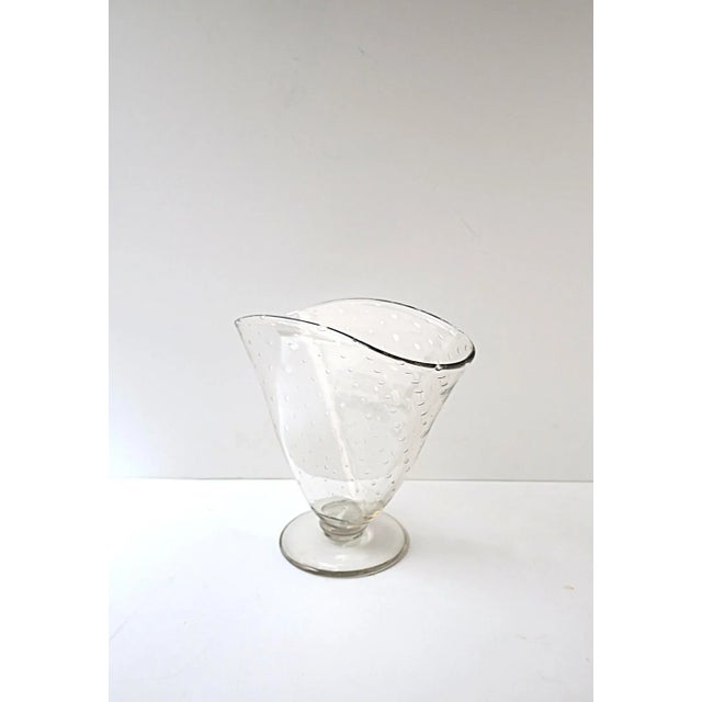 A clear transparent blown-glass art glass vase with a controlled bubble design. Vase is oblong fan shaped with circular...