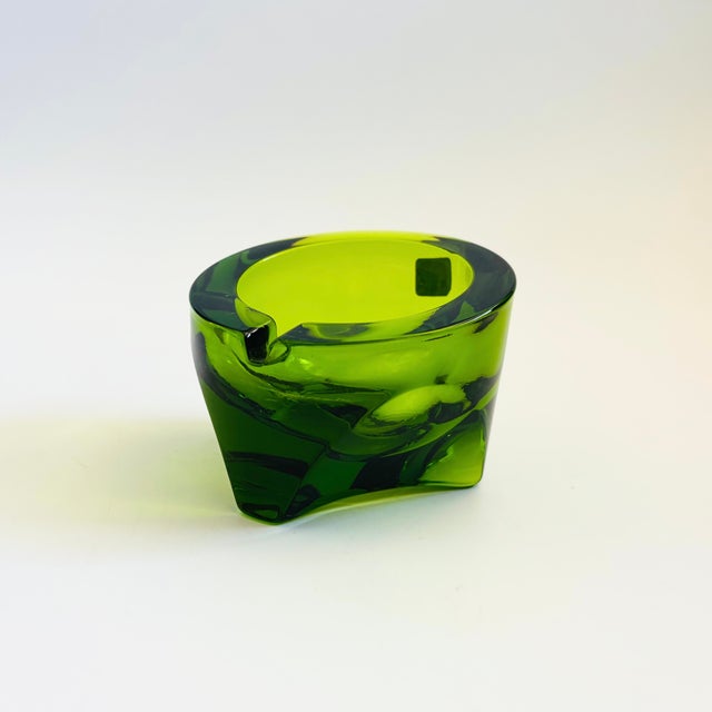 A mid century glass ashtray by Viking Glass. Made of thick, heavy glass in a vibrant green color. Round shape that tapers...