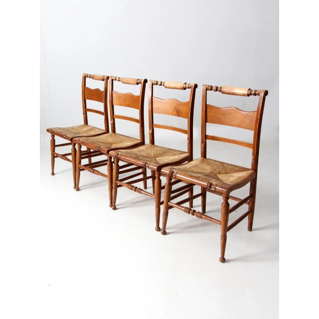 This is a collection of four vintage Tell City Furniture chairs. The Hitchcock style chairs feature rush seats and a...
