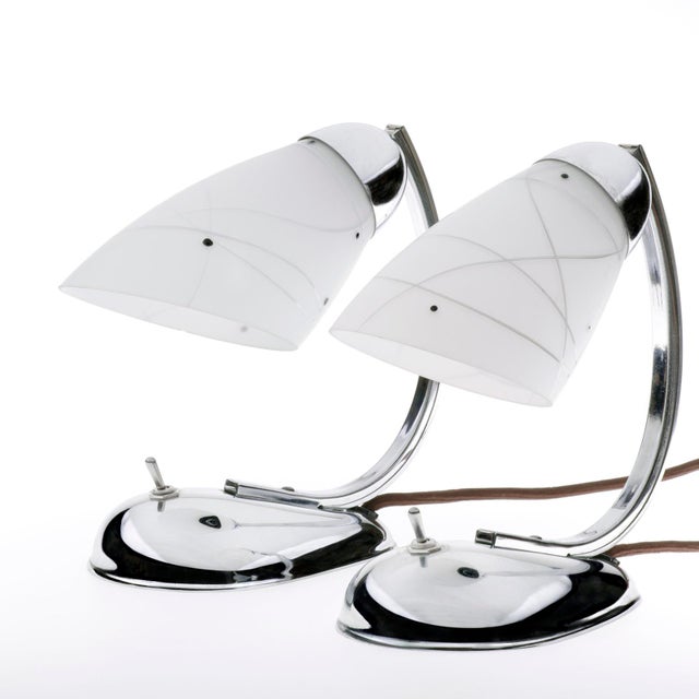 An extremely rare Art Deco pair of bedside / table lamps, made of glass and chrome-plated metal by the Czech Designer...