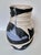 This striking handmade pottery vase features a dynamic interplay of black and white glazes with a distinctive blue accent....