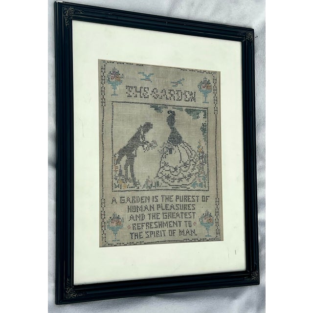 Undated vintage framed cross-stitch sampler featuring a garden theme with a classic silhouette illustration of a man and a...