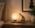 Compact Art Deco table lamp dating to the 1940s. A stylised animal figure in a brass-toned finish sits upright beside a...