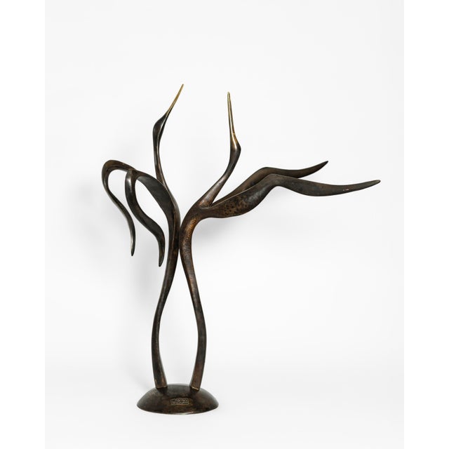 A contemporary animal bronze of two storks caught in their courtship dance, necks stretched to the sky and golden beaks...