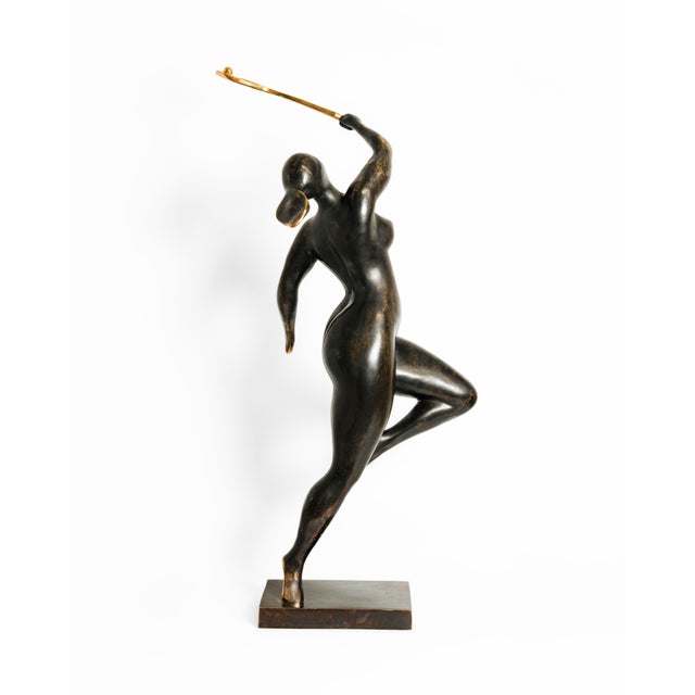 A contemporary figurative bronze of a woman mid-swing, racket raised high overhead, weight poised on one leg in the moment...