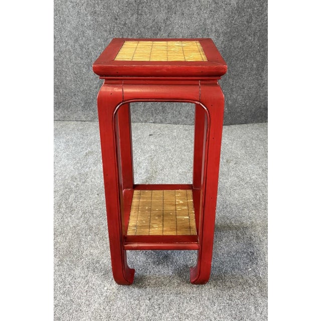 This Asian-inspired plant stand features a vibrant red lacquer-style finish accented by woven rush panels on both the top...
