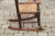 An English Georgian period plum wood child's rocking chair from the early 19th century, with rush seat, ladder back and...
