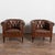 Pair of vintage brown leather barrel back club chairs featuring tufted button backs, self piping, and brass nail head trim...