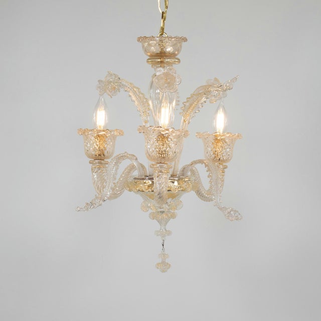 This vintage handcrafted gold-infused cristallo Murano chandelier has three scroll arms with chalice cups, utilizing a...