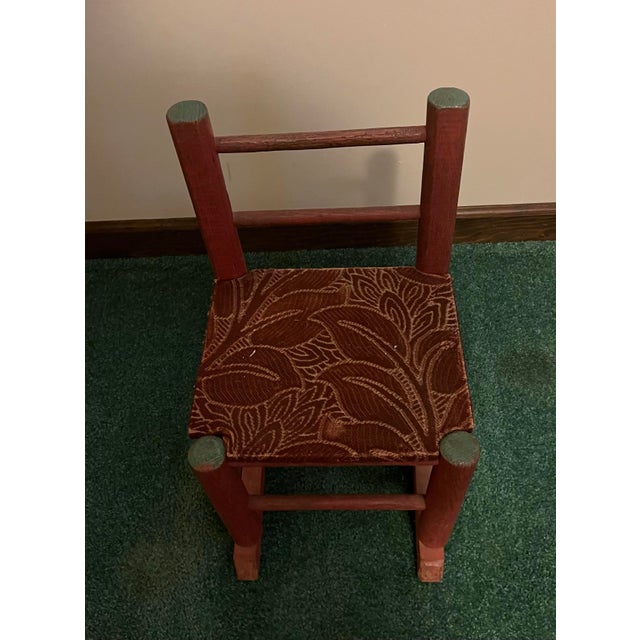 Unknown age child’s rocking chair in reddish brown with green accents in a farmhouse or cottagecore style. It measures...