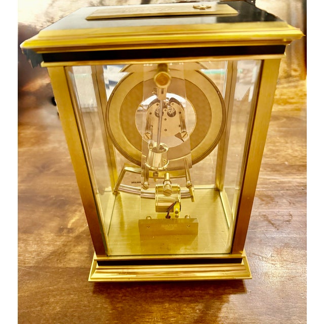 This clock features a polished brass rectangular frame, often characterized by a Hollywood Regency or Mid-Century Modern...