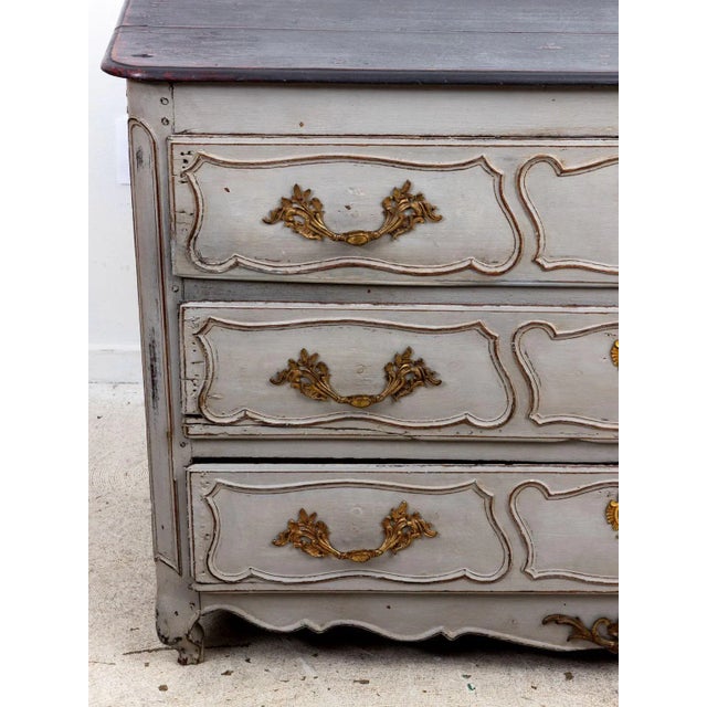 A late 19th Century Louis XIV style French commode with later gray paint. Brass pulls and escutcheons on three drawers....