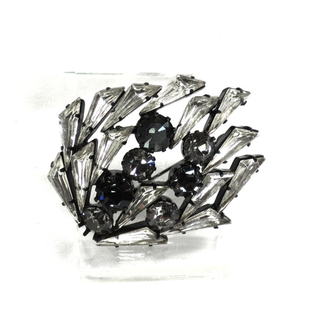 Vintage japanned black enamel brooch 1950s. Elongated triangular crystal stones flow around round crystals in clear and...
