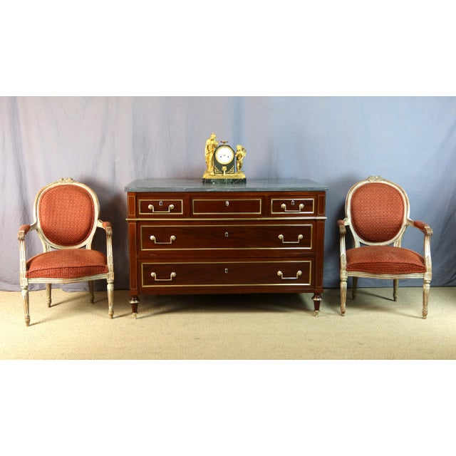 A Louis XVI commode with brass moldings, opening with five drawers: three in the upper section and two larger drawers...