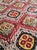 Hand-knotted rug with vibrant red and black, featuring a traditional geometric Ikat pattern with diamond and circular...